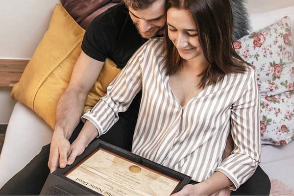 couple holding box and framed deed